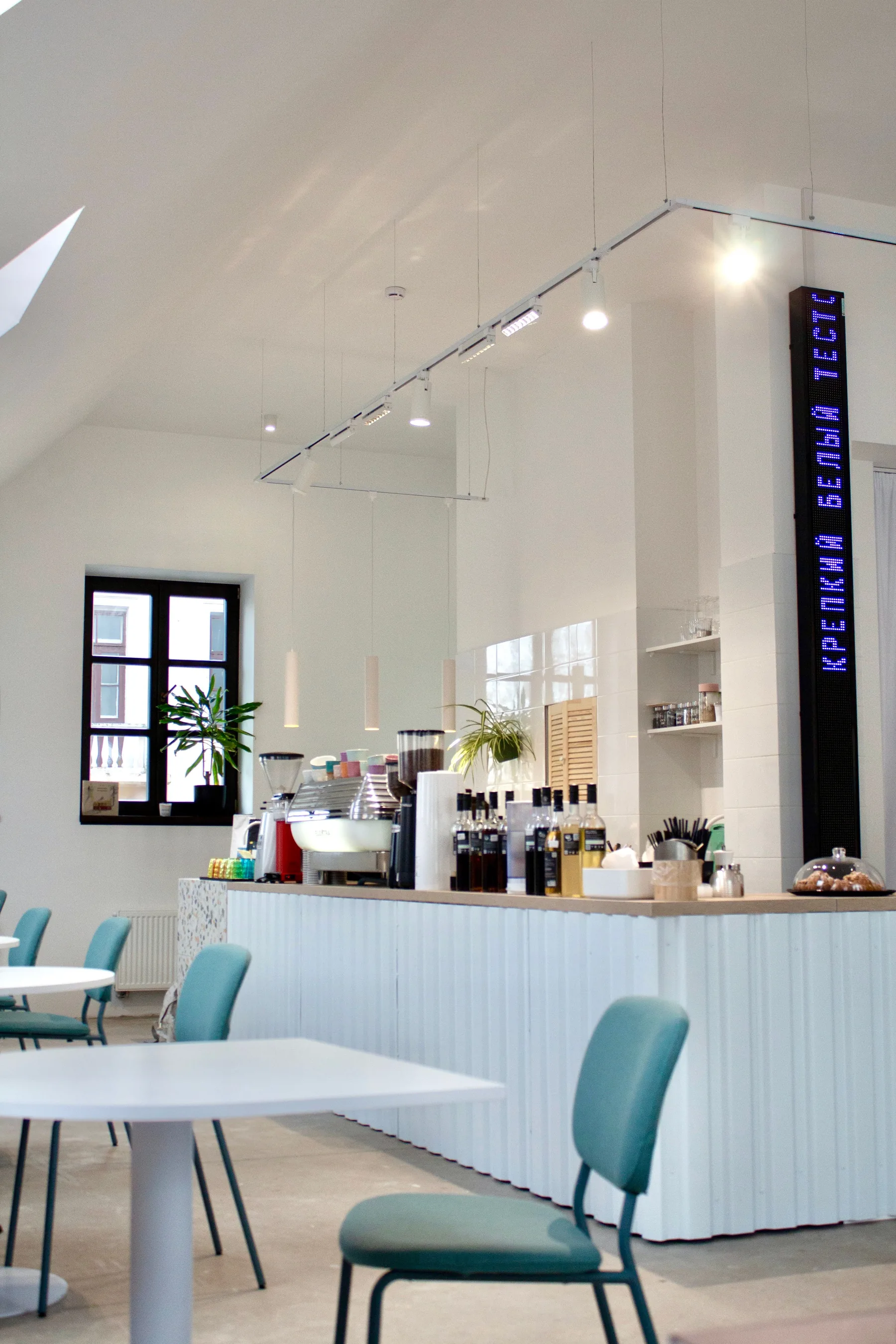 Interior claro e contemporâneo de uma cafeteria com balcão e mesas