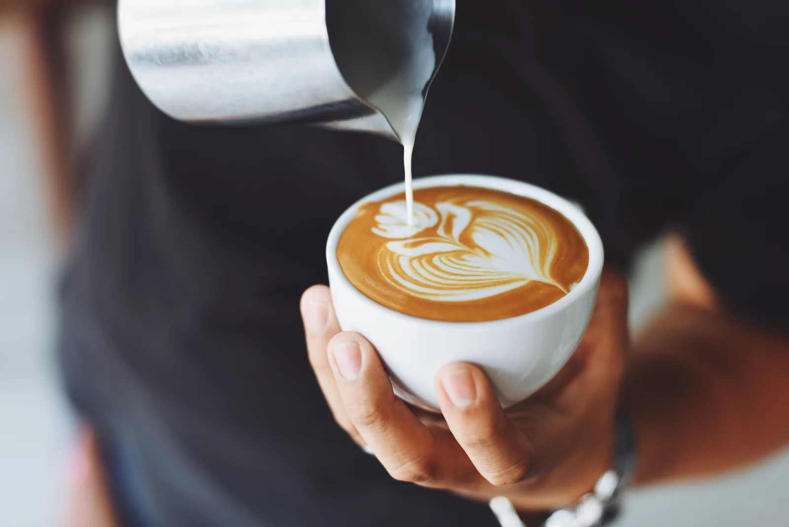 Barista preparando latte art em uma xícara de café